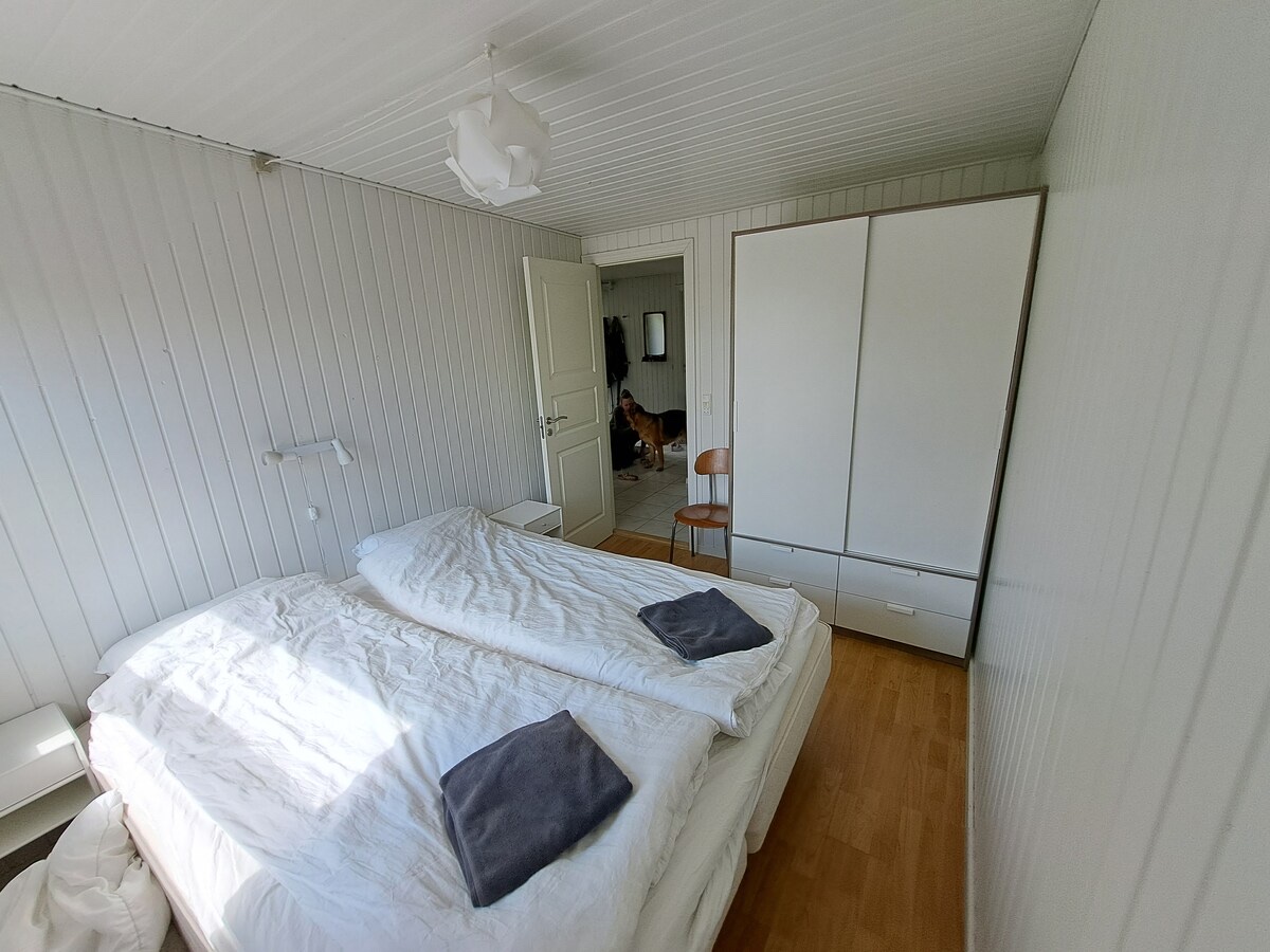 Lyst soveværelse med dobbeltseng og stort garderobeskab