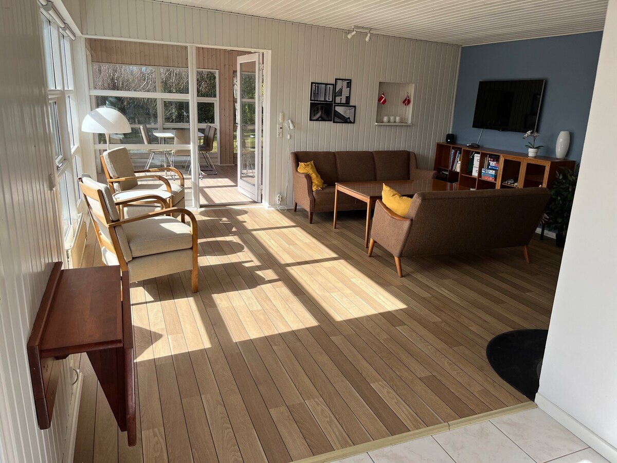 Lys stue med sofaer og åbning til den solrige havestue