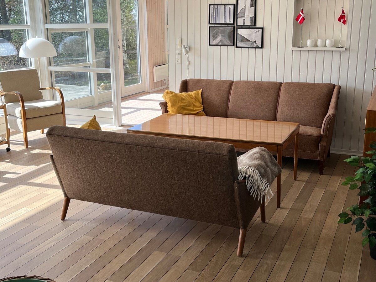 Stue med sofaarrangement og store vinduer mod haven